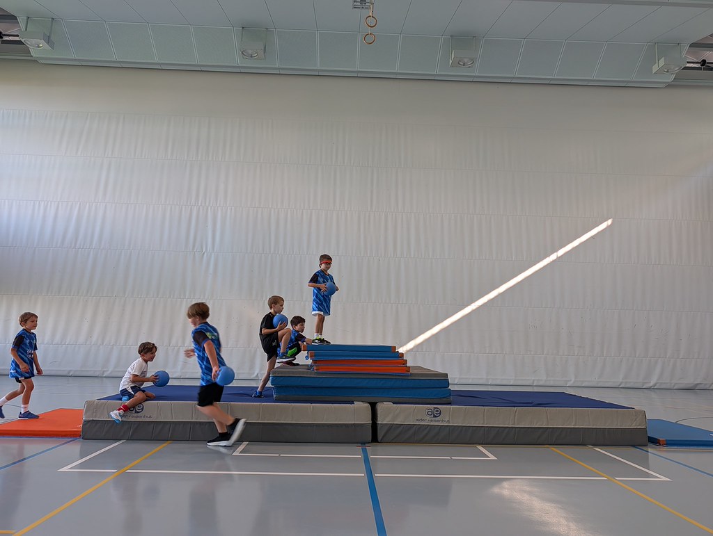 Kinder meistern gemeinsam einen Parcours in der Turnhalle.