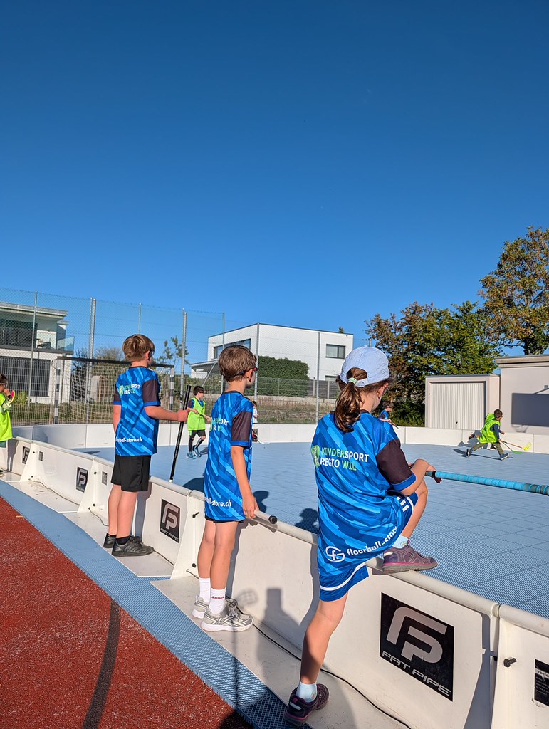 Kinder spielen draussen auf dem roten Sportplatz.