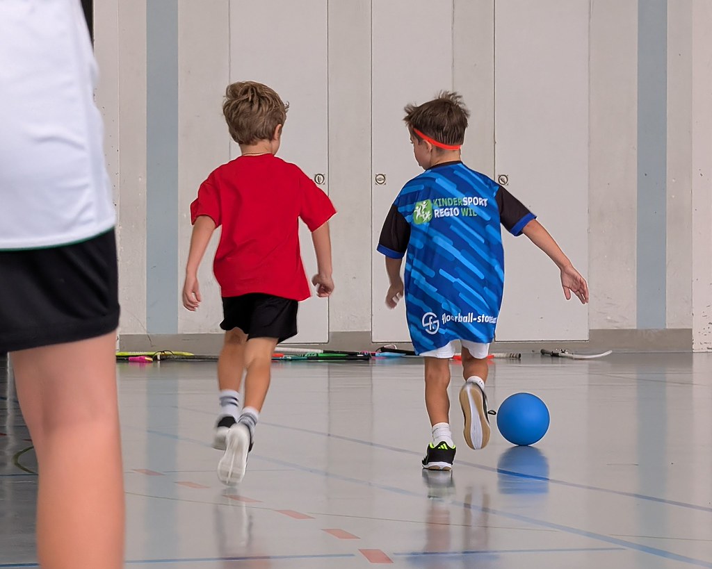 Zwei Kinder laufen während einer Unihockeyübung dem Ball nach.