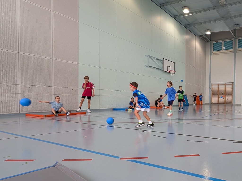 Kinder spielen in der Halle gemeinsam mit bunten Bällen.